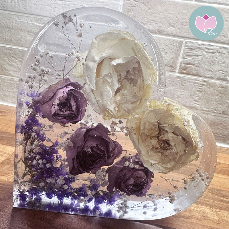 Image of a resin heart containing white and purple flowers preserved from a much loved mother's funeral. Created by Orchid Memories